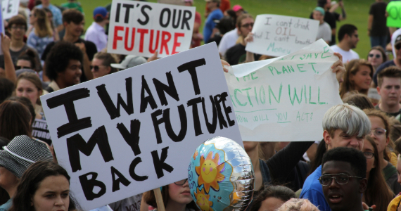 A group of young people at a climate rally holding a sign that says "I want my future back"
